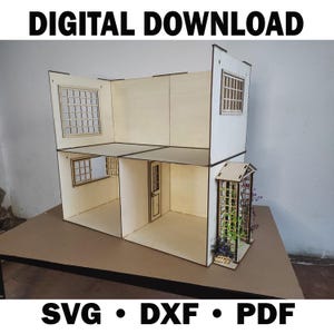 May include: A two-story wooden dollhouse with a light wood finish and dark brown trim. The dollhouse features windows, a door, and a small trellis. The text "DIGITAL DOWNLOAD" and "SVG • DXF • PDF" are displayed.