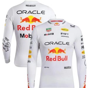 May include: White long-sleeved shirt with Red Bull Racing branding, including the Oracle and Red Bull logos. The shirt displays various sponsor logos and has a crew neck. The material appears lightweight and suitable for sports or casual wear.