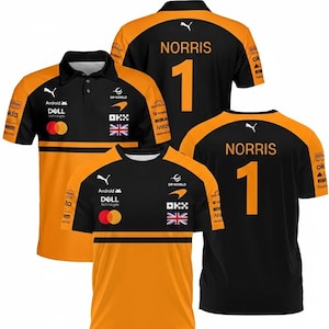 Puede incluir: Camisetas de equipo de carreras negras y naranjas con el nombre "NORRIS" y el número "1" en la espalda. Las camisetas presentan logotipos de patrocinadores, incluyendo "DELL" y "OKX", y una bandera británica. Una camiseta es un polo, las otras son de cuello redondo.