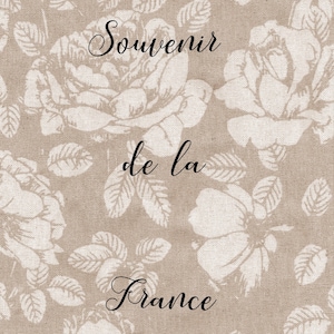 May include: A beige fabric background with a white floral pattern. The text "Souvenir de la France" is printed in black cursive font.