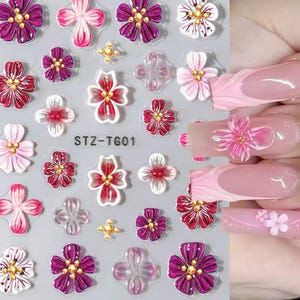 May include: Nail art stickers with floral designs in pink, red, white, and purple. Some flowers have gold centres. The sheet includes the text "STZ-TG01".