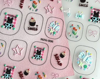 May include: A sheet of nail art stickers featuring various designs. The stickers include butterflies, cupcakes, stars, and a bear with a bow. The text "SMILE", "DREAM", and "WE LOVE PENNY" are also present. The stickers are on a pink and clear background.
