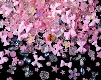 May include: Assortment of pink and purple resin embellishments, including bows, hearts, stars, flowers, and butterflies. These decorative charms are perfect for adding a touch of whimsy to crafts, jewellery, and other projects.