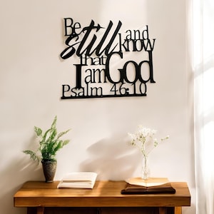 May include: Black metal wall art with the words "Be still and know that I am God" and "Psalm 46:10".