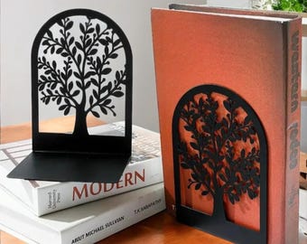 May include: Two black metal bookends shaped like trees with leafy branches. The bookends are holding up two books, one with a red cover and the other with a white cover.