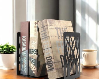 May include: Black metal bookends with a geometric design, holding up three books. The books have titles that include "Kasabian", "Let It Bleed", and "The Freedom Dom".
