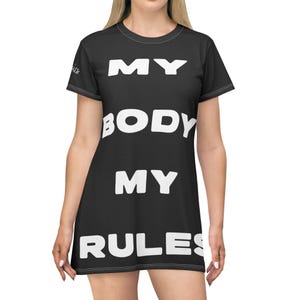 May include: Black dress with the text "MY BODY MY RULES" in large white block letters. The dress has short sleeves and a scoop neckline. The dress is made of a soft, flowing fabric.