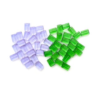 May include: A selection of rectangular glass beads in two colours: translucent lavender and bright green. The beads are scattered on a white background, suitable for jewellery making or craft projects.