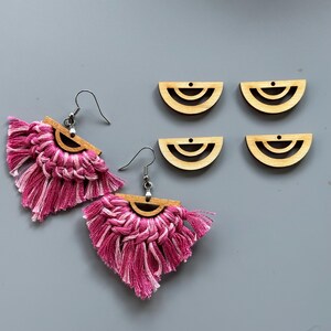 May include: Two pairs of earrings with pink and white fringe tassels and wooden half-circle charms with a double-ring design.