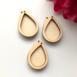 May include: Three unfinished wooden teardrop-shaped earring blanks with holes at the top.