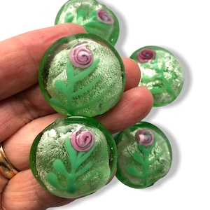May include: Five green glass beads with silver leaf and a pink flower design.