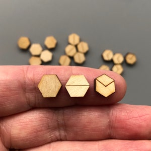 May include: Three wooden hexagon shapes with different geometric designs. The hexagons are light brown and have a natural wood finish.