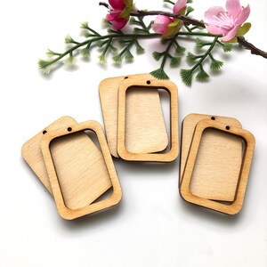 May include: Five unfinished wooden rectangular frames with a hole at the top for hanging. The frames have a cutout in the centre, creating a smaller rectangle.