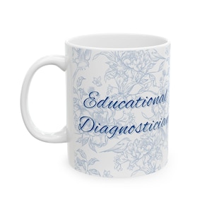 May include: White ceramic mug featuring a blue floral design and the text "Educational Diagnostician". The pattern includes flowers, leaves, and birds. The mug has a curved handle for easy gripping.