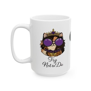以下が含まれることがあります： 紫色のサングラス、王冠、蝶ネクタイ付きの襟を身に着けた漫画の猫が描かれた白いセラミックマグ。マグには「Try Not to Die」というテキストが筆記体で書かれています。