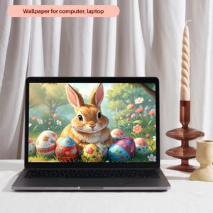 Puede incluir: Un portátil muestra un fondo de pantalla de Pascua con un conejo marrón y huevos decorados en un jardín. Una vela retorcida y un candelabro están a la derecha. El texto "Wallpaper for computer, laptop" está en la parte superior.