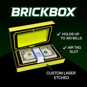 May include: A yellow and black BRICKBOX safe, open to reveal a stack of US dollar bills. The safe has an Air Tag slot and holds up to 300 bills. The text "BRICKBOX" is at the top, and "CUSTOM LASER ETCHED" is at the bottom.