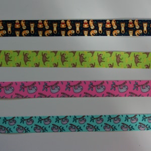 May include: Four different ribbons with a repeating pattern of sloths hanging from branches. The ribbons are black, green, pink, and turquoise.