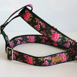 Puede incluir: Arnés para perro negro con un patrón floral rosa y una etiqueta de cuero marrón que dice "Bones Collars".