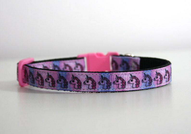 Pu&ograve; includere: Un collare rosa per cani con un motivo ripetuto di unicorni dei cartoni animati. Il collare ha un interno nero e una fibbia in plastica rosa brillante. Il design dell'unicorno utilizza colori rosa, viola e blu.