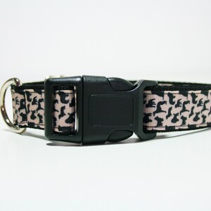 May include: A pink and black dog collar with a black plastic buckle. The collar is decorated with a repeating pattern of black dog silhouettes.