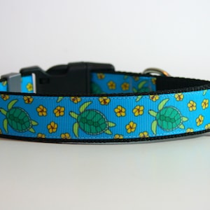 May include: A blue dog collar with a pattern of green sea turtles and yellow flowers.