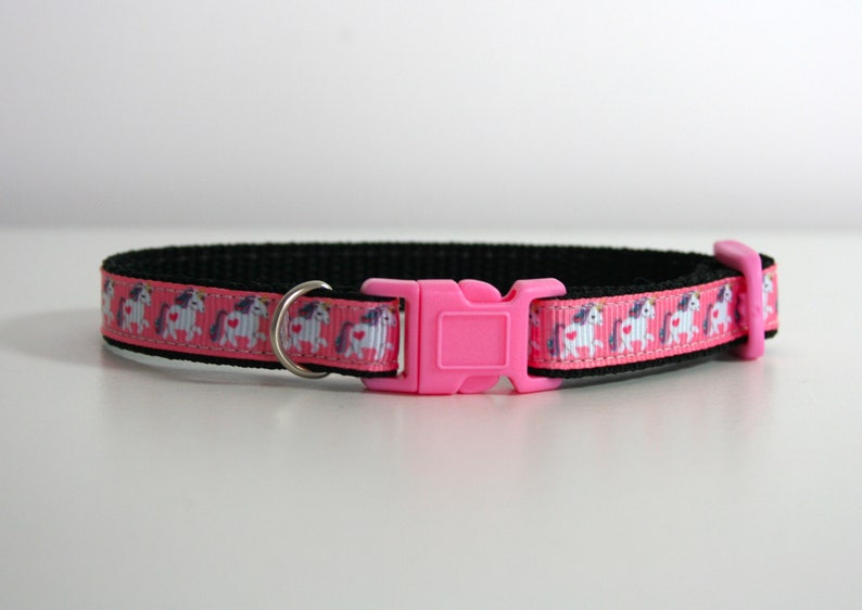 May include: Pink and black cat collar with a pink plastic buckle and a white unicorn print.