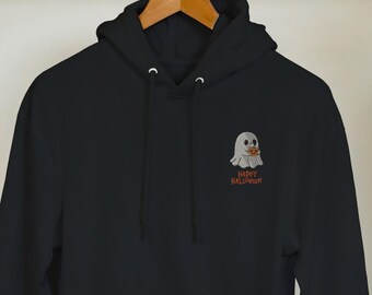 May include: Black hooded sweatshirt with a front pocket and drawstring. The sweatshirt features a small embroidered ghost graphic with the text "Happy Halloween" in orange. The hoodie is hanging on a wooden hanger.