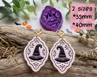 May include: A pair of white and purple witch hat earrings with gold-tone hooks, accompanied by a matching purple plastic clay cutter. The text reads DIGITAL STL FILE, 2 sizes, 35mm, 40mm, and CLAY CUTTER FOR EARRING. The design features a central witch hat.