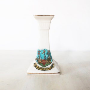 Peut inclure: Bougeoir en céramique blanche avec une bordure dorée et un blason bleu et or avec le mot "Weymouth" dessus.