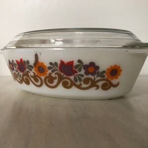 May include: White oval baking dish with a glass lid. The dish has a floral pattern in shades of orange, brown, purple, and green.