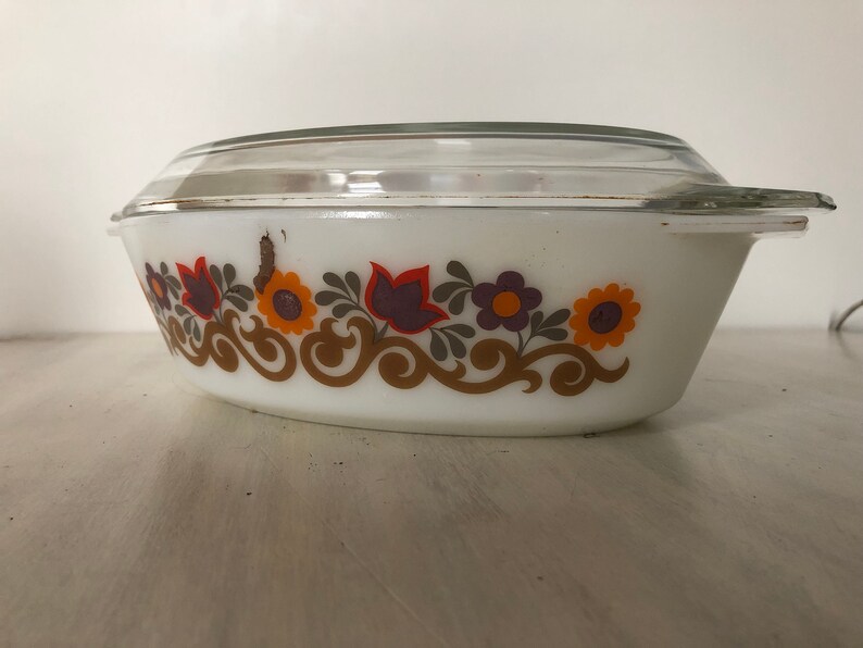 May include: White oval baking dish with a glass lid. The dish has a floral pattern in shades of orange, brown, purple, and green.