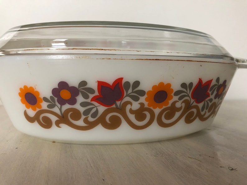 May include: White oval casserole dish with a lid. The dish has a floral pattern in shades of orange, yellow, purple, and brown.