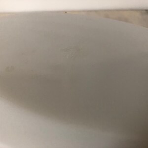 May include: White ceramic bowl with a smooth, glossy finish. The bowl has a slight indentation on the bottom.