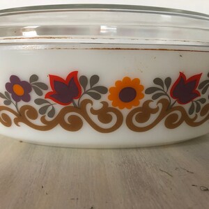 May include: White oval baking dish with a glass lid. The dish has a floral pattern in shades of orange, purple, and brown.