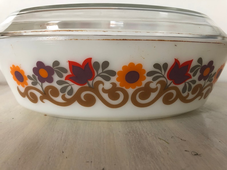 May include: White oval baking dish with a glass lid. The dish has a floral pattern in shades of orange, purple, and brown.