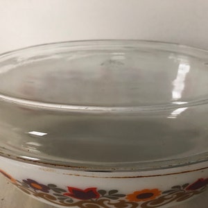May include: White ceramic baking dish with a clear glass lid. The dish has a floral pattern in shades of brown, orange, and yellow.