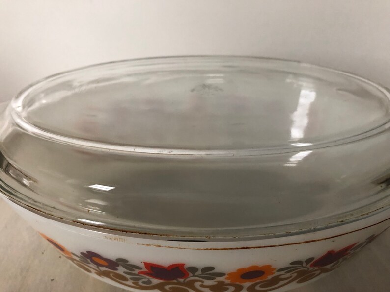 May include: White ceramic baking dish with a clear glass lid. The dish has a floral pattern in shades of brown, orange, and yellow.