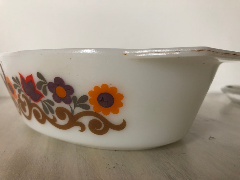 May include: White oval baking dish with a floral design in shades of orange, purple, and brown. The design features stylized flowers and leaves.