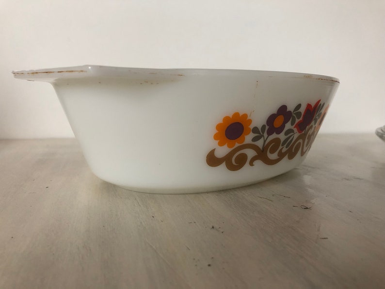 May include: White oval baking dish with a floral design in shades of orange, brown, purple, and green. The design features stylized flowers and swirls.