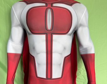 Puede incluir: Un disfraz de superhéroe rojo y blanco en un maniquí. El disfraz presenta un torso rojo con un emblema blanco, brazos blancos y guantes rojos. Una capa roja es visible en la parte posterior. El maniquí tiene una cabeza negra.