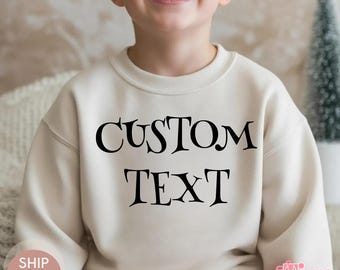 May include: A cream-colored sweatshirt with the words "CUSTOM TEXT" in black, worn by a child. The sweatshirt has a crew neck and long sleeves. The word "NATURAL" is in a small box in the upper left corner.