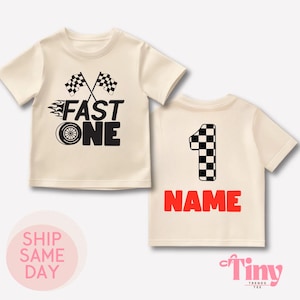 Puede incluir: Una camiseta de color crema con un diseño de bandera a cuadros en blanco y negro, las palabras "FAST ONE" y una huella de neumático. La parte posterior de la camiseta tiene un número "1" a cuadros en blanco y negro y la palabra "NAME" en rojo.