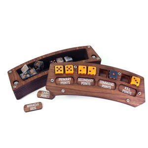 May include: A wooden dice tray and point tracker set. The set includes a rectangular box for dice storage and a curved board with slots for dice and labels for Primary, Secondary, Command, and Kill Points. Additional labels read Cabal Points and Miracle Dice.