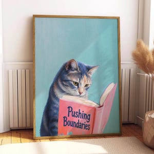 Könnte beinhalten: Ein gerahmter Kunstdruck mit einer grau-orangen getigerten Katze, die ein rosa Buch liest, auf dessen Einband der Text Pushing Boundaries steht. Die Katze ist vor einem einfarbigen hellblauen Hintergrund in vertikaler Ausrichtung dargestellt.