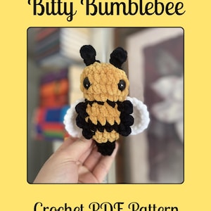 May include: A crocheted bumblebee with a yellow body, black stripes, and black antennae. The bee has white wings and black eyes. The text "Bitty Bumblebee" and "Crochet PDF Pattern" are displayed on a yellow background.