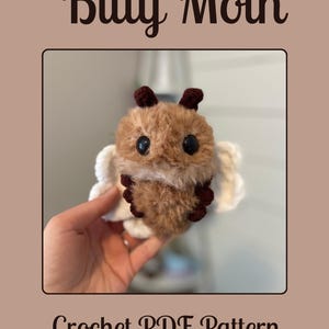 May include: A crocheted moth with brown and tan fur, dark brown antennae, and large black eyes. The moth has white wings and is labeled "Bitty Moth" and "Crochet PDF Pattern". The Etsy shop name is also included.