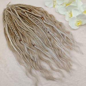 May include: A set of blonde and white synthetic dreadlocks with brown beads. The dreadlocks are wavy and have a natural look.