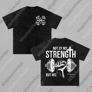 May include: Black t-shirt with a front design of dumbbells and the text "Philippians 4:13". The back of the shirt features the text "NOT BY MY STRENGTH BUT HIS" with a cross and a hand holding a barbell. A fitness-themed apparel item.