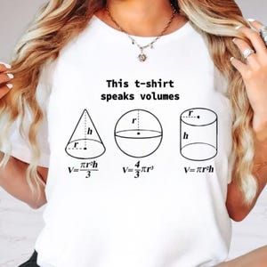 May include: A white t-shirt featuring the black text This t-shirt speaks volumes above three geometric shapes: a cone, a sphere, and a cylinder. Each shape includes its respective radius r, height h, and mathematical volume formula printed below.